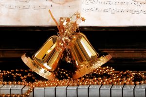 Piano keys decorated with golden Christmas decorations, close up