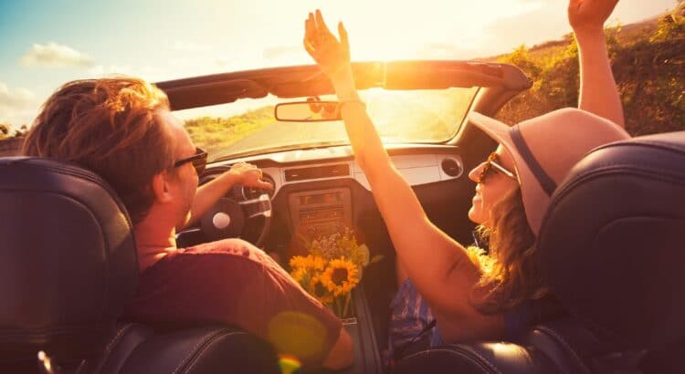 Happy Young Couple Driving Along Country Road in Convertible at